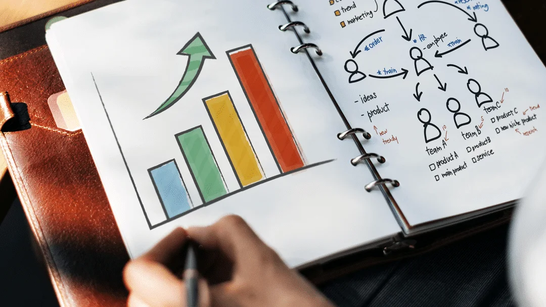 Foto de um caderno com um gráfico colorido em uma página e na outra há desenhos que demonstram um esquema de processo.